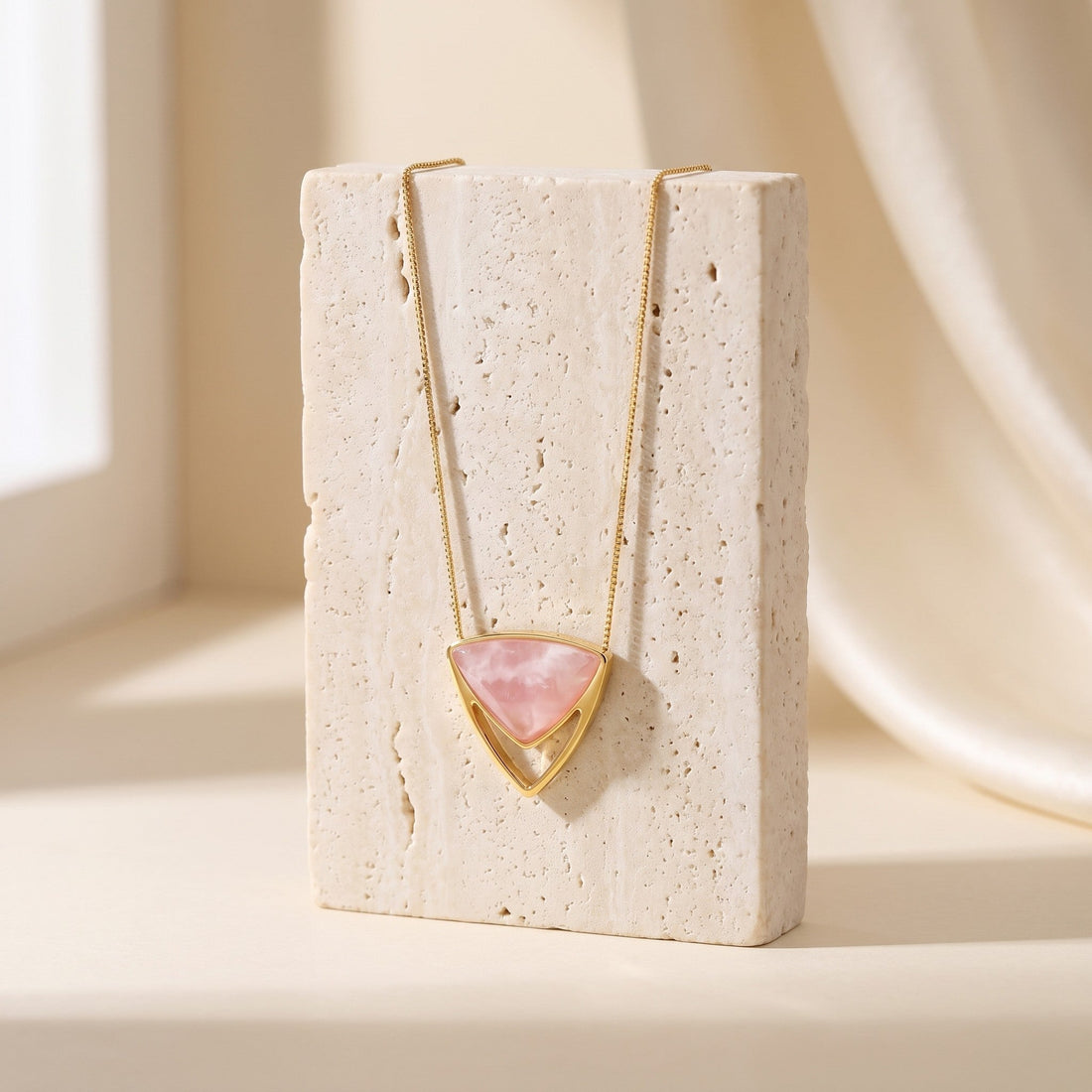 Colar Equilíbrio com pingente triangular de quartzo rosa multifacetado em banho de ouro 18k, pendurado num bloco de travertino, semijoia Aimer Joias