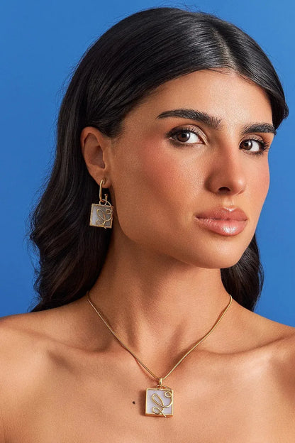O Brinco Forma com Ágata Branca em Banho de Ouro 18K oferece versatilidade no conceito 2 em 1, com aro liso e pingente geométrico removível. A Ágata Branca simboliza serenidade e paz. Com design contemporâneo de linhas em metal sobre a pedra, esta joia é ideal para expressar clareza e elegância no seu dia a dia.